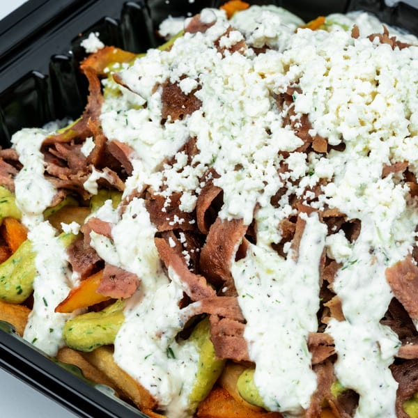 Shawarma Shack's Mediterranean fries topped with gyro meat, white sauce, green sauce, and feta cheese.